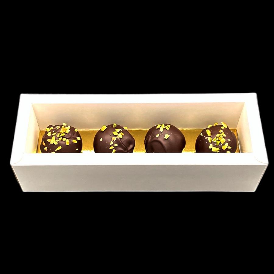 4 extra große handgefertigte Mozartkugeln von Pralinenart in einer weißen Schachtel mit goldenem Boden auf schwarzem Hintergrund